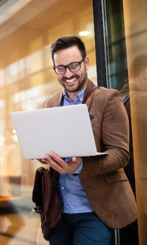 man standing with laptop showing the happiness on his face